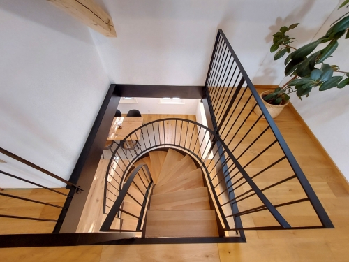 Escalier bois et métal, demi tournant avec limons métallique cintrés, garde-corps à barreaudage et marches en chêne massif